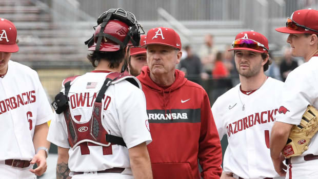 Arkansas Razorbacks coach Dave Van Horn talking with catcher Parker Rowland waiting on relief pitcher Koty Frank.